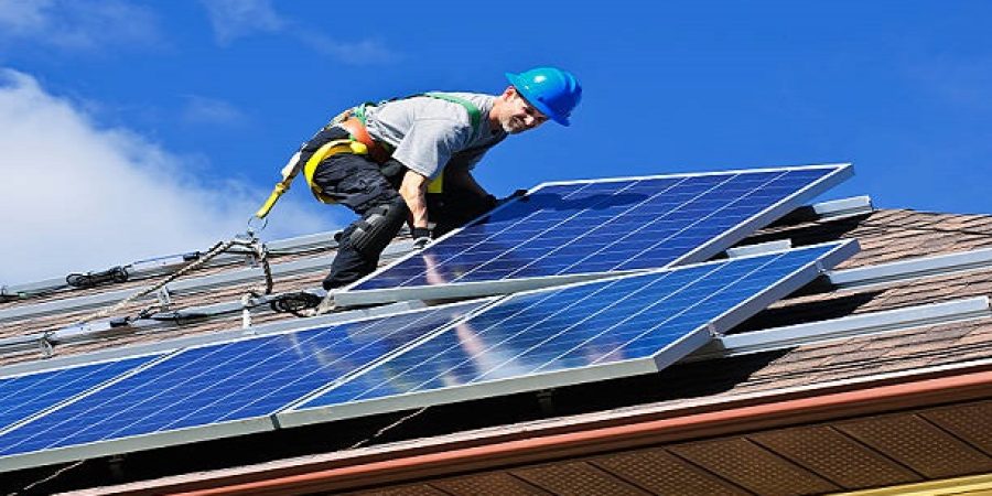 Man installing alternative energy photovoltaic solar panels on roof Man installing alternative energy photovoltaic solar panels on roof