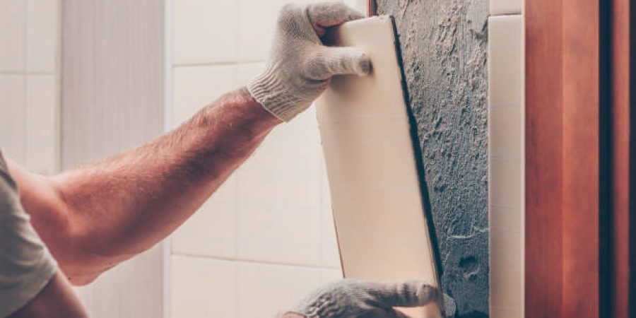 Worker breaks the remnants of tiles off the wall Worker breaks the remnants of tiles off the wall